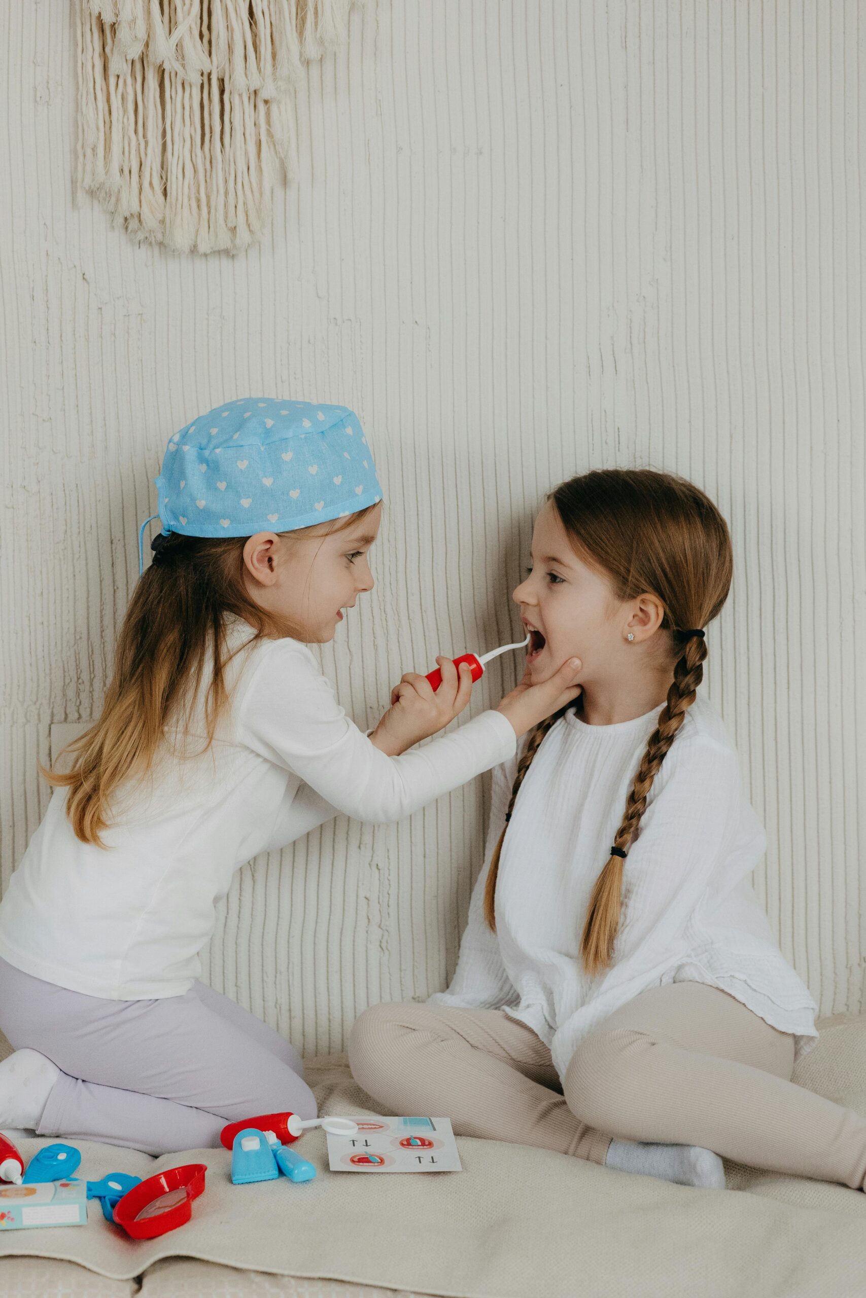 Two little girls sitting on the floor and brushing their teeth